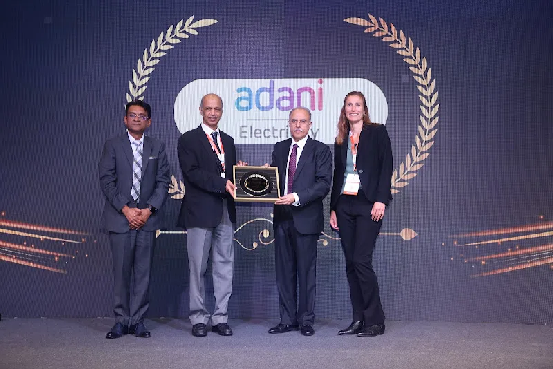 Award recipients in front of the Adani Electricity stage display