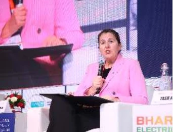 A woman in a pink jacket speaking into a microphone during a Day 1 discussion